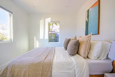 a white bedroom with a bed with pillows on it at Relaxing 4BR LA Home Private Pool & Fire Pit in Los Angeles