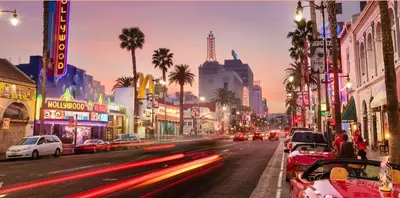 a city street with cars driving down a street with palm trees at Polished 1BR Hollywood Apt w Rooftop Pool & Views in Los Angeles