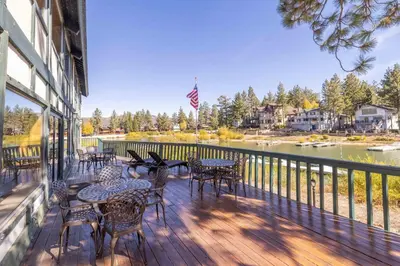 a deck with tables and chairs and a view of a river at Lakeview Getaway Game Rm, Pool, Spa, Sauna! in Big Bear Lake