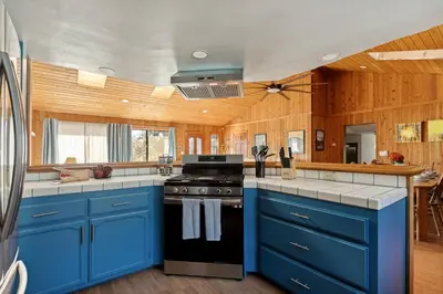 a blue kitchen with a stove and blue cabinets at Solstice Shores Chalet, Hot Tub and Lake Views in Fawnskin