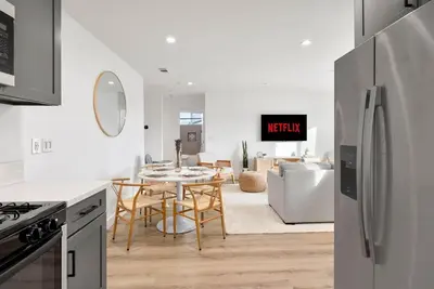 a kitchen and living room with a table and a refrigerator at Luxe 3BR South Bay - Comfort and Close to Beach in Harbor City