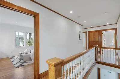 a staircase in a home with white walls and wood floors at Hollywood Heritage Villa in Los Angeles