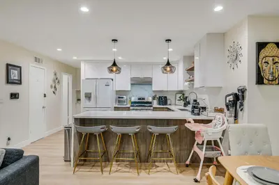 a kitchen with white cabinets and a bar with stools at 20 min to Disneyland - Spacious Family Home Near All the Fun in Westminster