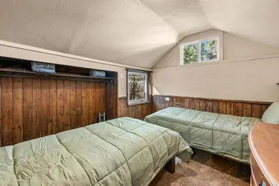two beds in a bedroom with wood paneling at Appleview - Walk to Village/Lake, Lake View, Hot Tub, BBQ in Big Bear Lake