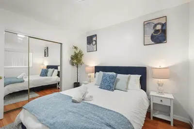 a bedroom with a large bed and a mirror at Steps to Beach - Beach Essentials Provided! in Long Beach