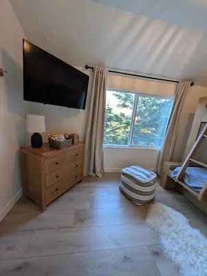 a bedroom with a flat screen tv and a large window at Yama Cabin - 5 min walk to the village, EV plug, hot tub, kid & pet friendly in Lake Arrowhead