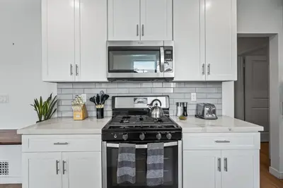 a kitchen with white cabinets and a stove top oven at Belmont Shore Getaway with Hot Tub and Firepit in Long Beach