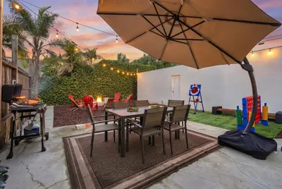 a patio with a table and chairs and an umbrella at Belmont Shore Getaway with Hot Tub and Firepit in Long Beach