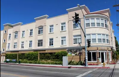 a building on the corner of a street with a traffic light at Woodland Oasis 2BR With FREE PARKING in Canoga Park