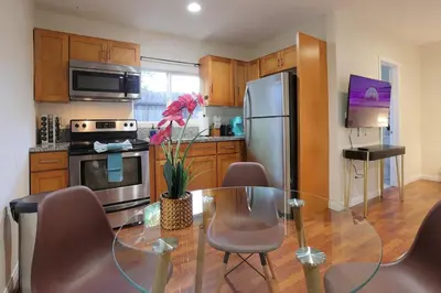 a kitchen with a glass table and a stainless steel refrigerator at Modern Oasis Studio - near LAX, SoFi, USC, DTLA in Los Angeles