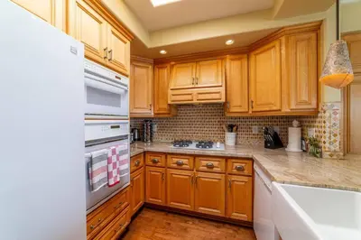 a kitchen with wooden cabinets and a white refrigerator at Ocean View Penthouse 2 Bdrm 2 Bath w garage 2 Blocks to sand in Manhattan Beach