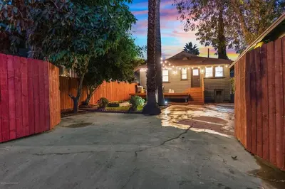 a driveway in front of a house with a red fence at Historical Craftsman with Modern Amenities in Los Angeles