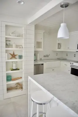 a white kitchen with a counter and stools at Exquisite Carpinteria Beach Cottage, Steps Away From The Beach in Carpinteria