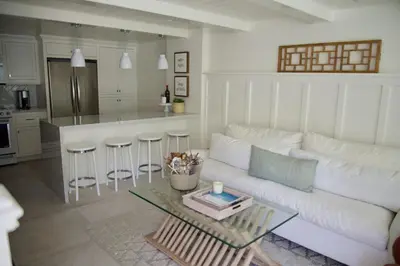 a living room with a white couch and a table at Exquisite Carpinteria Beach Cottage, Steps Away From The Beach in Carpinteria