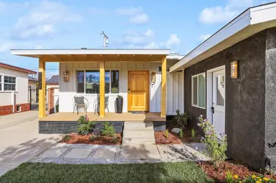 a small house with a yellow front door at Quintessential SoCal indoor outdoor living with POOL in Long Beach