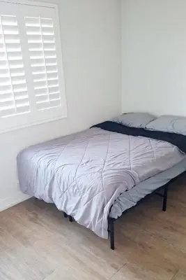 a bed in a white room with a window at Normandie Vibes Hostel in Los Angeles