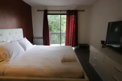 a bedroom with a large white bed with a window at Cozy Beverly Hills Hotel Style apartment in Los Angeles