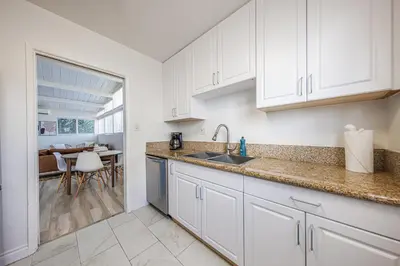 a kitchen with white cabinets and a sink and a table at Spacious 2-Bedroom Duplex in Beverly Hills Residential Area in Los Angeles