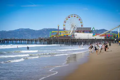 people walking on the beach near a pier with a ferris wheel at Casa Blanca Coastal Condo Rooftop Heated Pool in Los Angeles