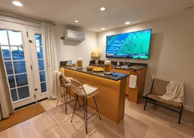 a kitchen with a bar with a tv on the wall at Walk 2min to BEACH! Boho 3-Bedroom BEACH Pad with AC, Patio, Laundry & Mid Size Parking in Long Beach