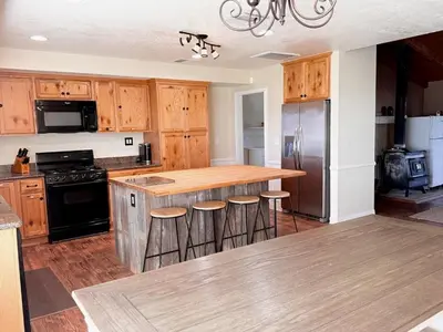 a kitchen with wooden cabinets and a island with bar stools at Desert Ranch Retreat in Lancaster
