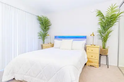 a white bedroom with a bed and two plants at Hollywood Hills Haven - Resort Living Near Universal Studios & Warner Bros in Los Angeles