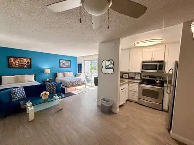 a living room with a blue couch and a kitchen at Serene Stay with Pool Access & Balcony in Los Angeles
