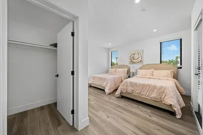 two beds in a bedroom with white walls and wood floors at 5BR Gorgeous Melrose Villa with Parking in Los Angeles