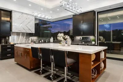 a kitchen with a large island with black cabinets at Ultra Luxury 5BR Beverly Hills Estate with Private Pool Spa and Canyon Views in Los Angeles