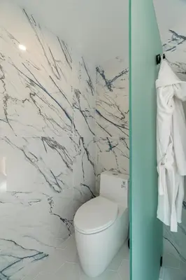 a bathroom with a white toilet and marble walls at Phenomenal King, Air, Rooftop Deck, Walk to Beach in Hermosa Beach