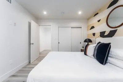 a white bedroom with a large bed and a mirror at Modern 3BR Retreat with Rooftop Deck Sleeps 8 in Los Angeles