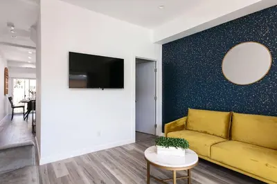 a living room with a yellow couch and a wall at Upscale 4BR Townhouse Sleeps 8 with Fast WiFi in Los Angeles