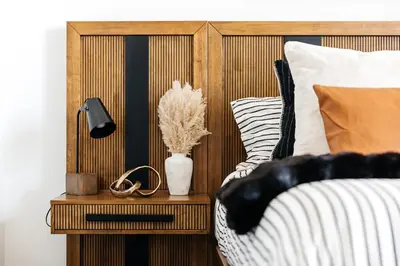 a bed with a wooden headboard and a vase on a night stand at Penthouse Muse, West Hollywood, Los Angeles in Los Angeles