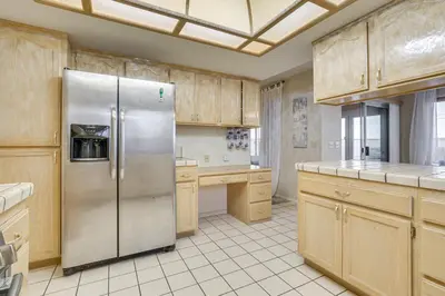 a kitchen with a stainless steel refrigerator and wooden cabinets at Golf, Fish and More! Peaceful Home in Helendale in Helendale