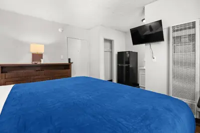a bedroom with a blue bed and a black refrigerator at Studio Lodge Hotel in Hewitt