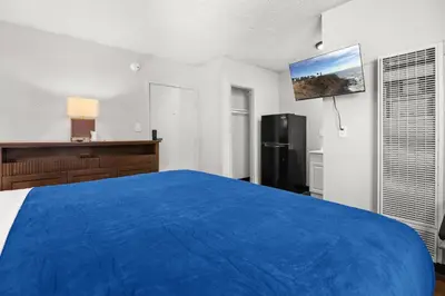 a bedroom with a blue bed and a refrigerator at Studio Lodge Hotel in Hewitt