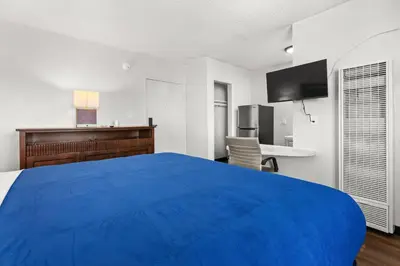 a large blue bed in a room with a desk at Studio Lodge Hotel in Hewitt