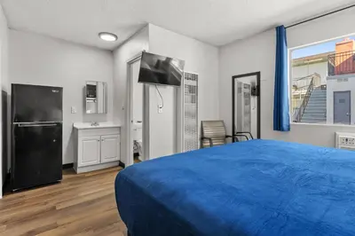 a bedroom with a blue bed and a tv at Studio Lodge Hotel in Hewitt