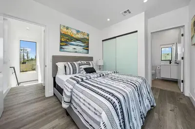 a white bedroom with a bed with a striped blanket at 2BR 2BA Villa in Melrose with Free Parking in Los Angeles