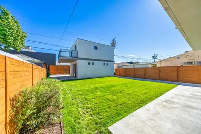 a yard with a white house and a fence at 7 BR double house with parking and a backyard in LA in Los Angeles