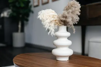 a white vase sitting on a table with feathers at City Sanctuary - Urban Hideaway in Los Angeles