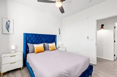 a bedroom with a large bed with a blue headboard at Charming 3BR Apartment | Near Disney + Arcade in Placentia