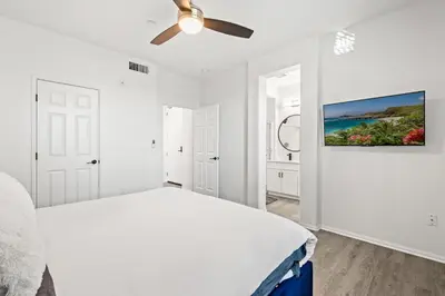 a white bedroom with a bed and a ceiling fan at Charming 3BR Apartment | Near Disney + Arcade in Placentia