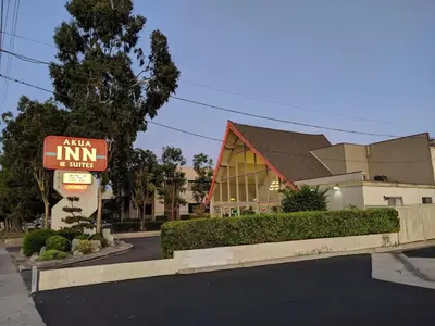 a building with a sign in front of a store at Akua Inn & Suites - Anaheim - Fullerton in Anaheim