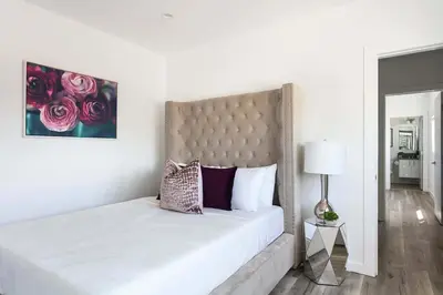 a white bedroom with a large bed with purple pillows at Spacious 4BR Townhouse with Free Parking Near DTLA in Los Angeles