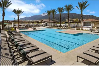 a large swimming pool with lounge chairs and palm trees at Ali's home in Fontana