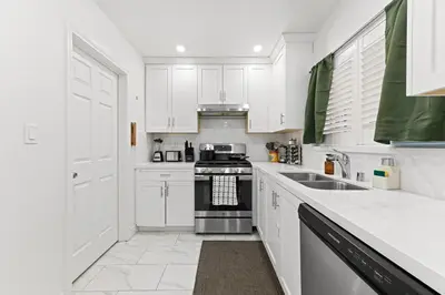 a white kitchen with a stove and a sink at Stylish Getaway with Hot Tub in Northridge Hospital Heliport