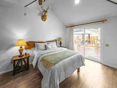a bedroom with a bed and a sliding glass door at Mountain Deer Cabin W Foosball & Fenced Backyard in Big Bear City