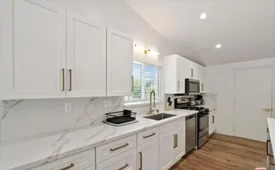 a white kitchen with white cabinets and a sink at stunning Poolside villa