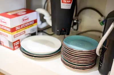 a stack of plates sitting on a counter next to a box at Modern Cozy Stay w Outdoor Patio & Grill in Pomona